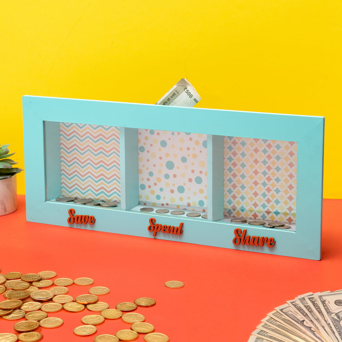 Money management tray with 'Save', 'Spend', and 'Share' compartments on a colorful background.