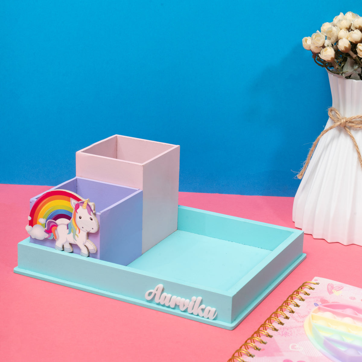 Desk organizer with unicorn and rainbow design on a pink surface with blue background