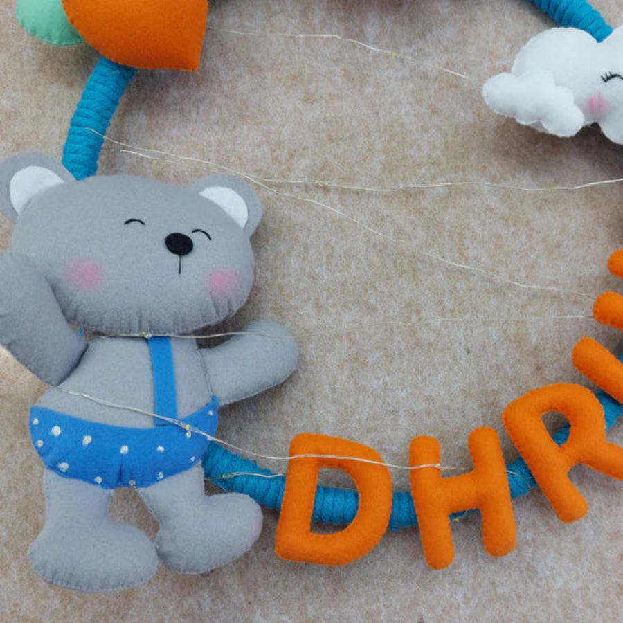 Toy with a teddy bear and cloud characters on a string, featuring the name 'DHRUZ' in orange letters.
