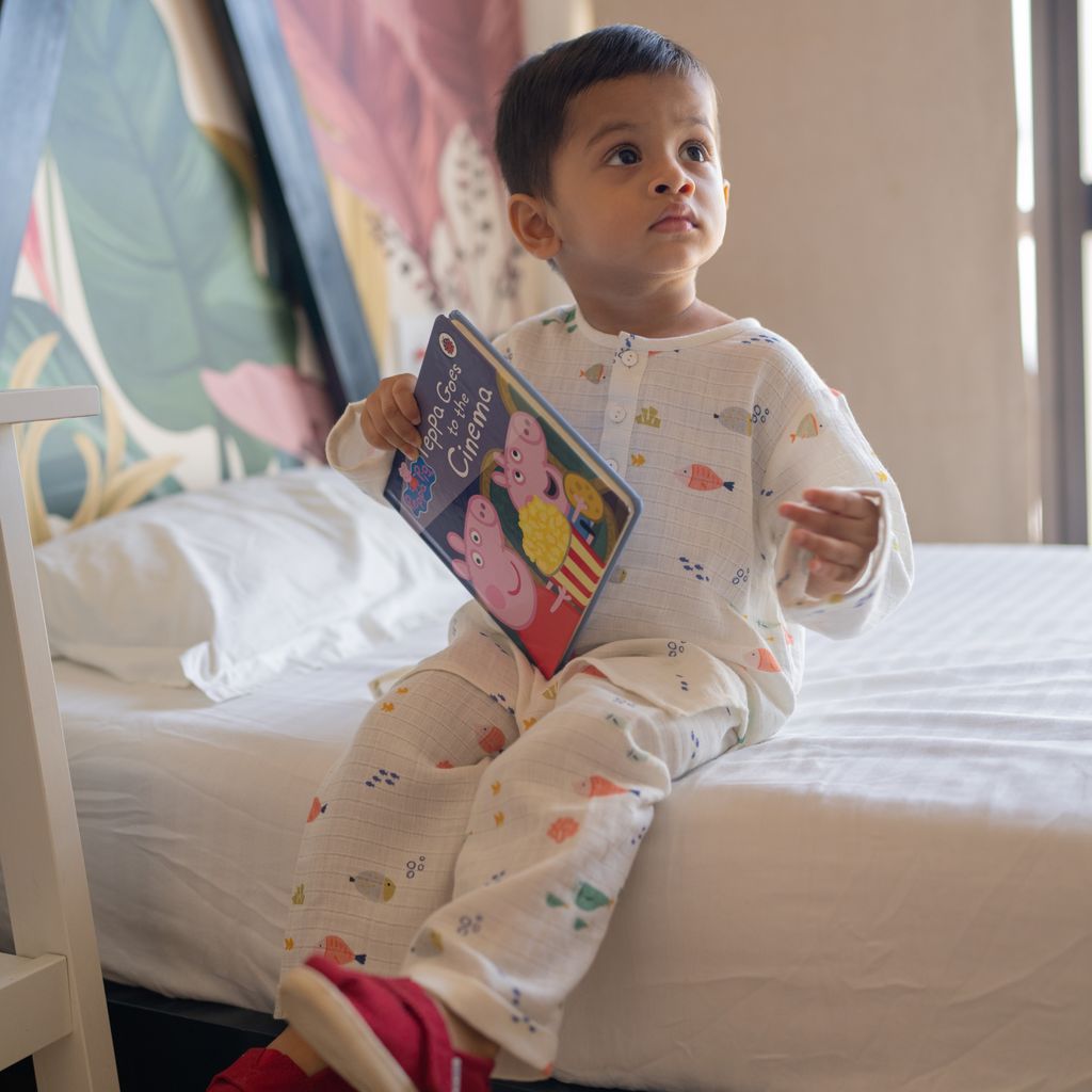 Child sitting on a bed holding a Peppa Pig book