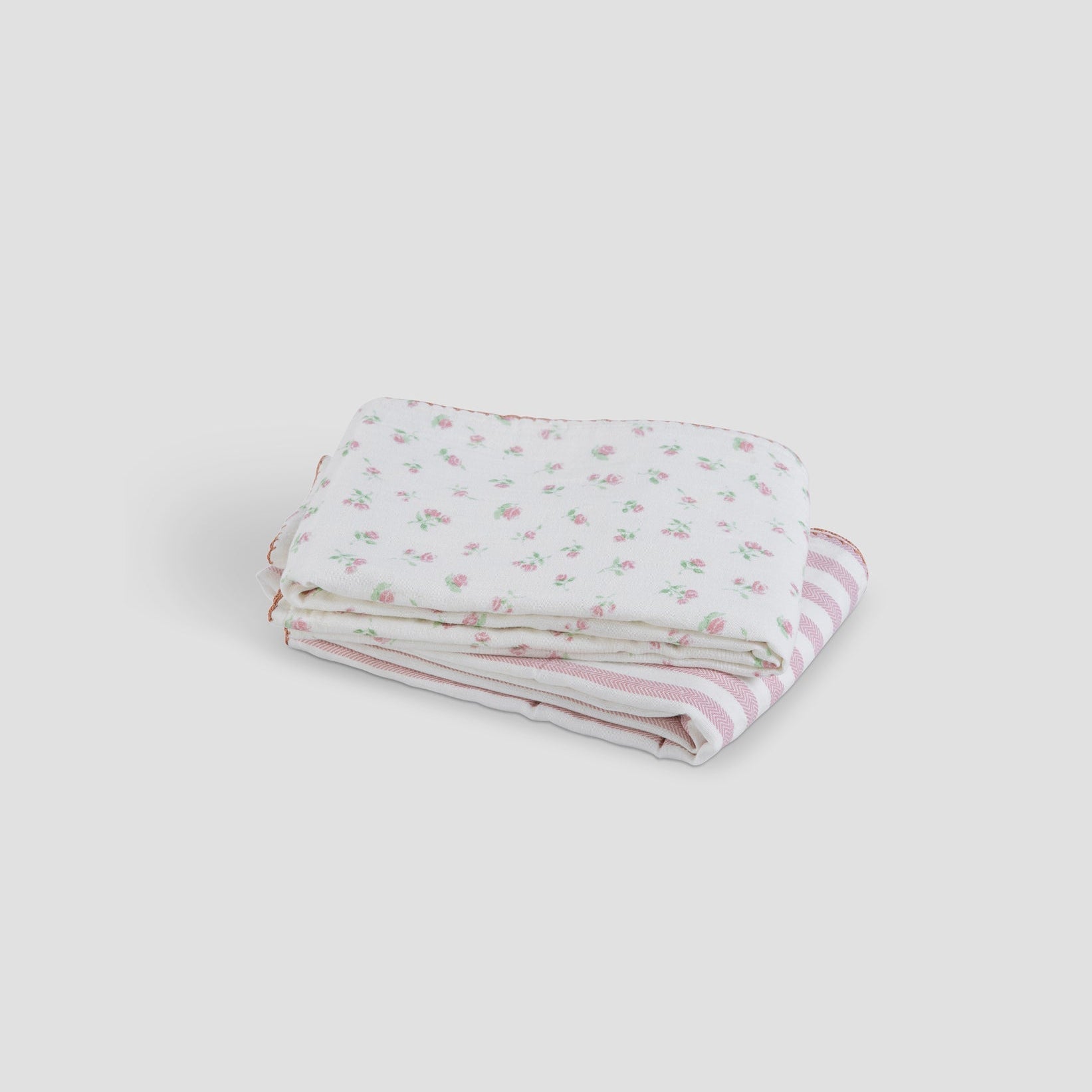 Folded pink and white striped fabric with floral pattern on a light gray background