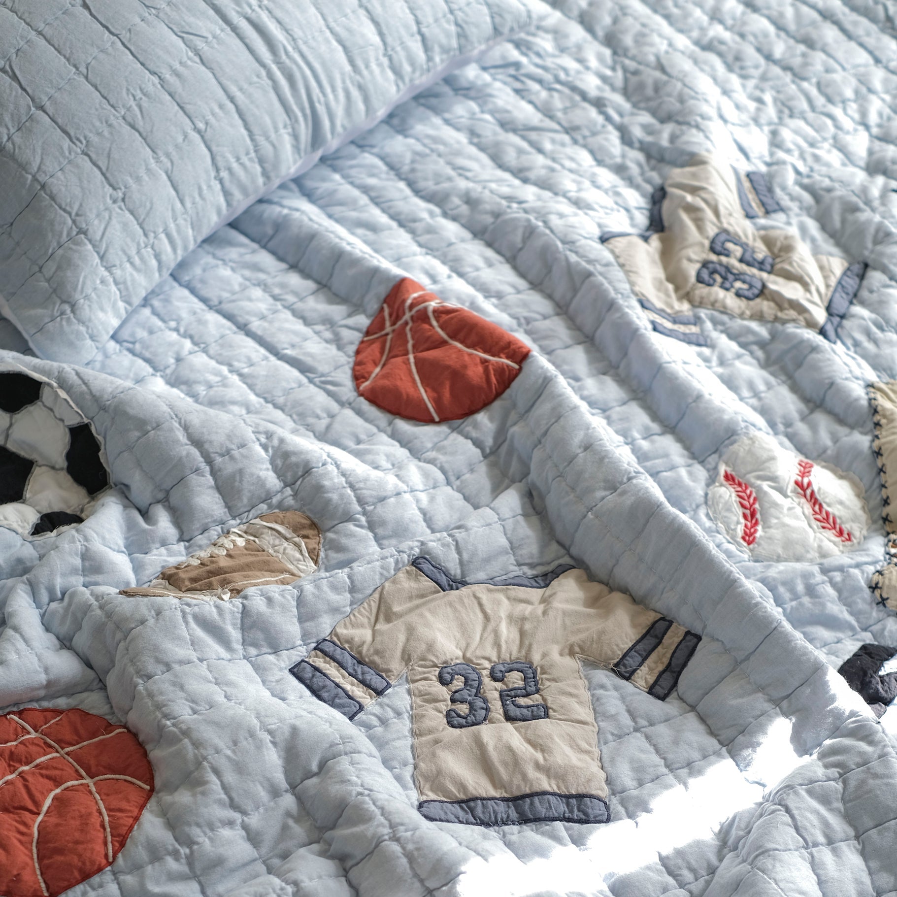Quilt with sports-themed appliqués including a basketball, baseball, and sports jersey.