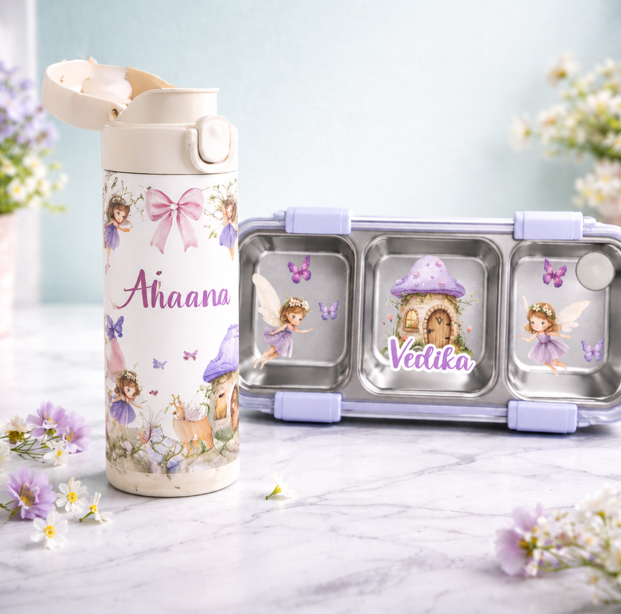 Personalized water bottle and snack container with fairy design on a light surface with flowers.