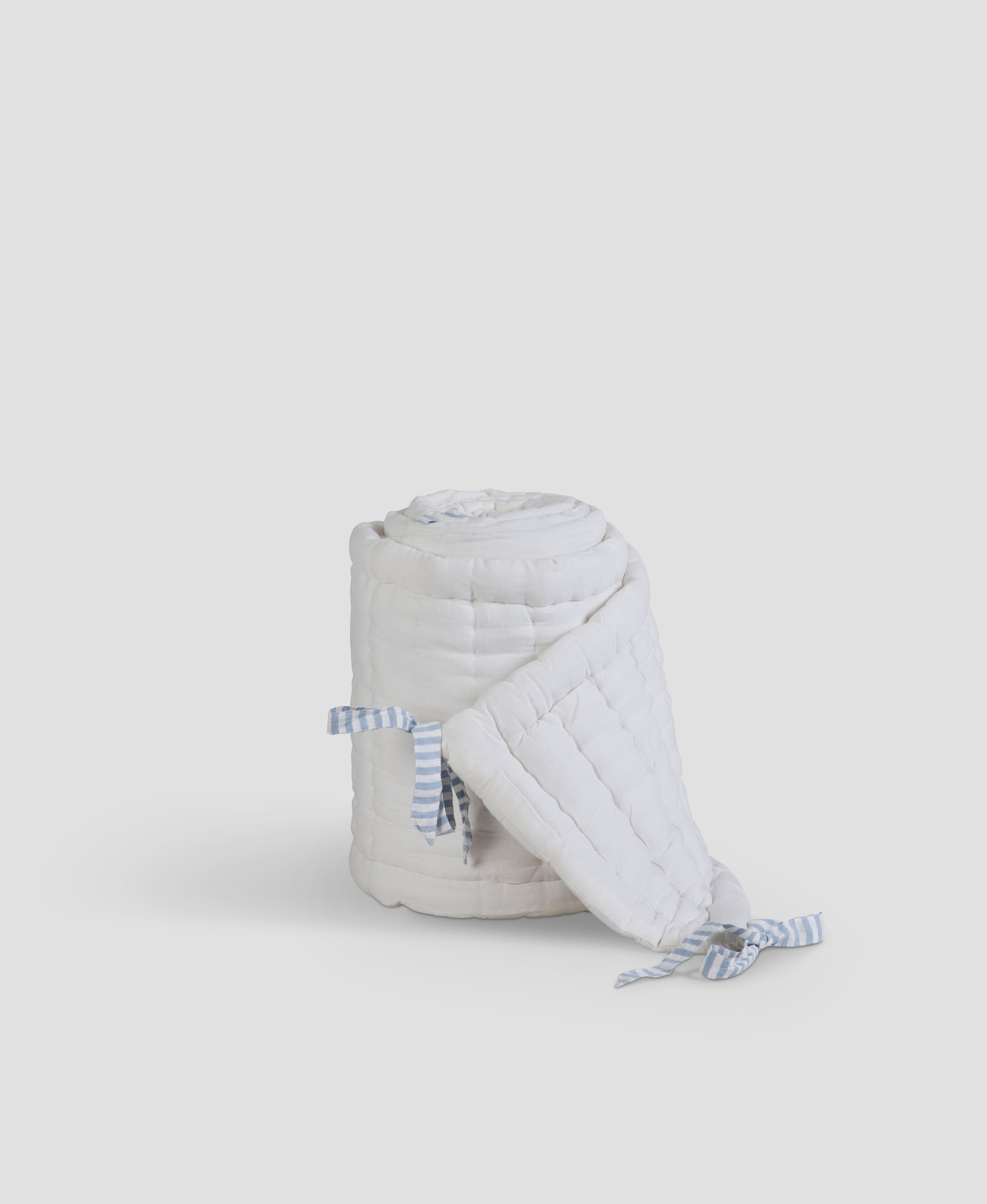 White quilted bag with blue straps on a light gray background