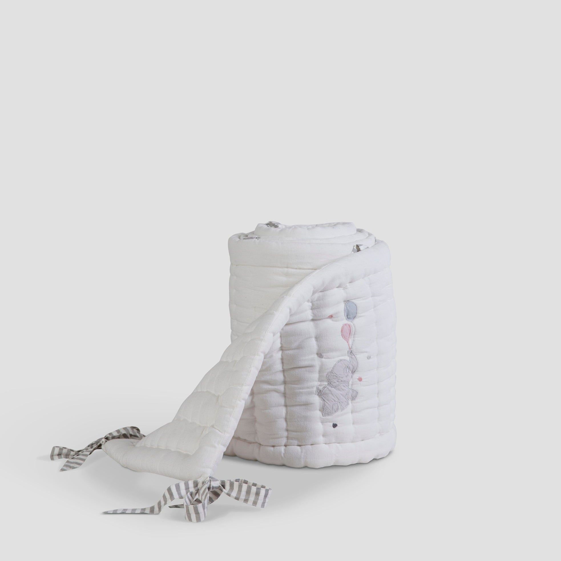 White woven basket with a white towel draped over it on a light gray background