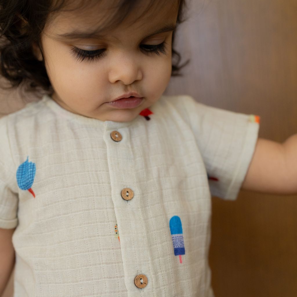 Child wearing a light-colored outfit with ice cream illustrations
