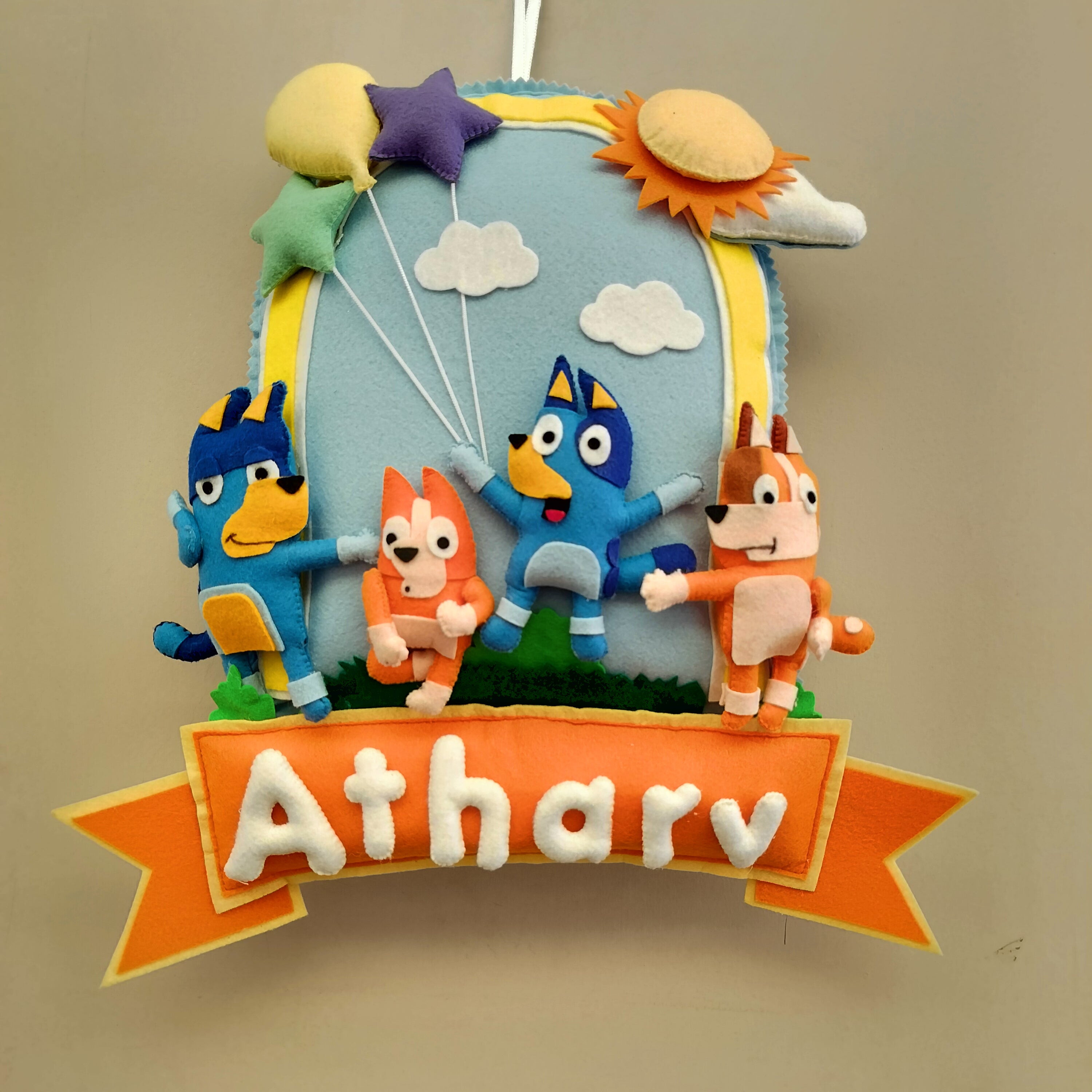 Children's decorative wall hanging with cartoon characters and 'Atharv' text on a beige background
