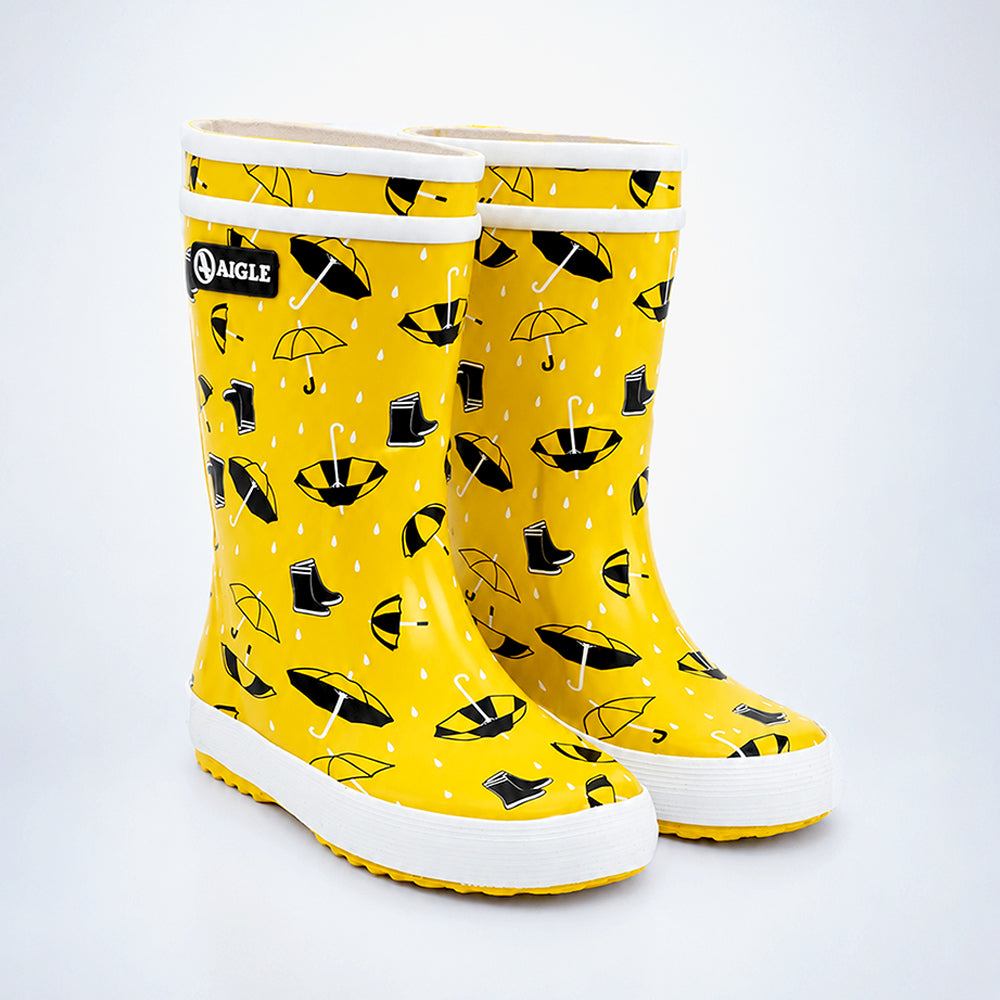 Yellow rain boots with black umbrella pattern on a white background