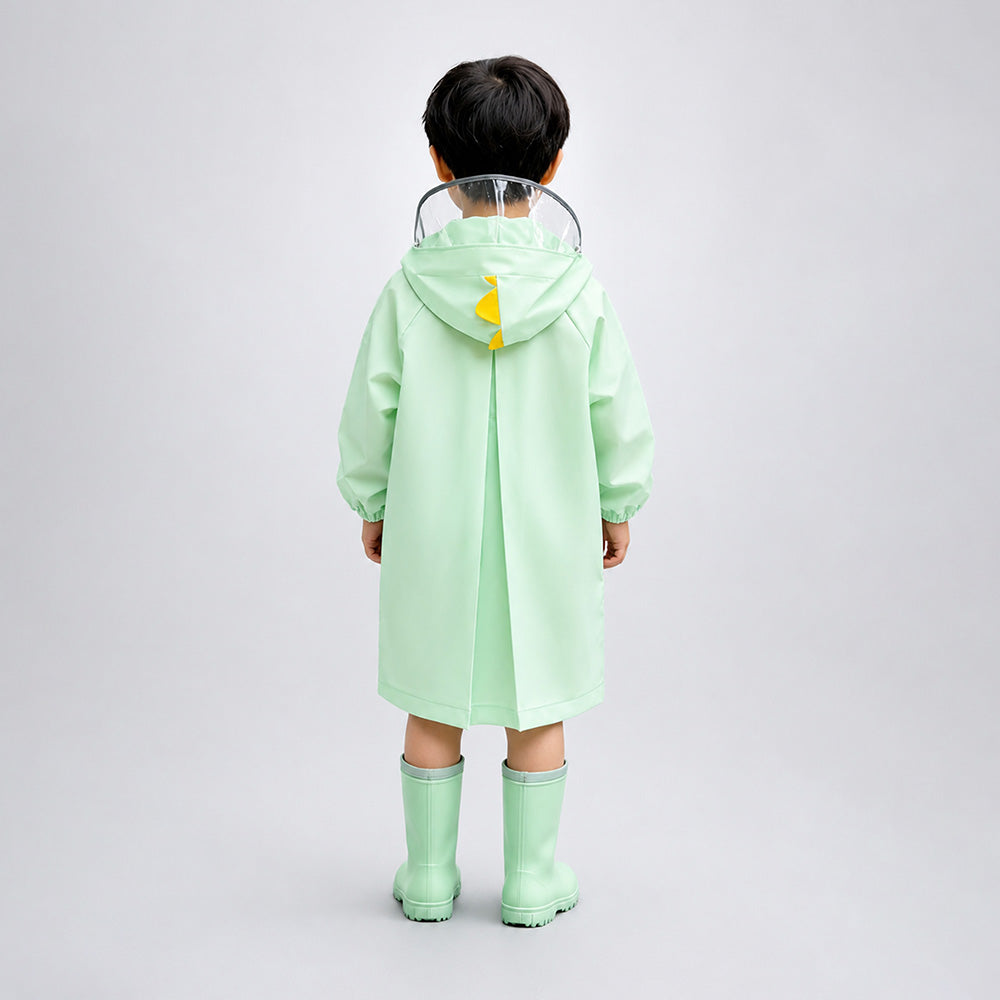 Child wearing a light green raincoat and matching rain boots on a plain background