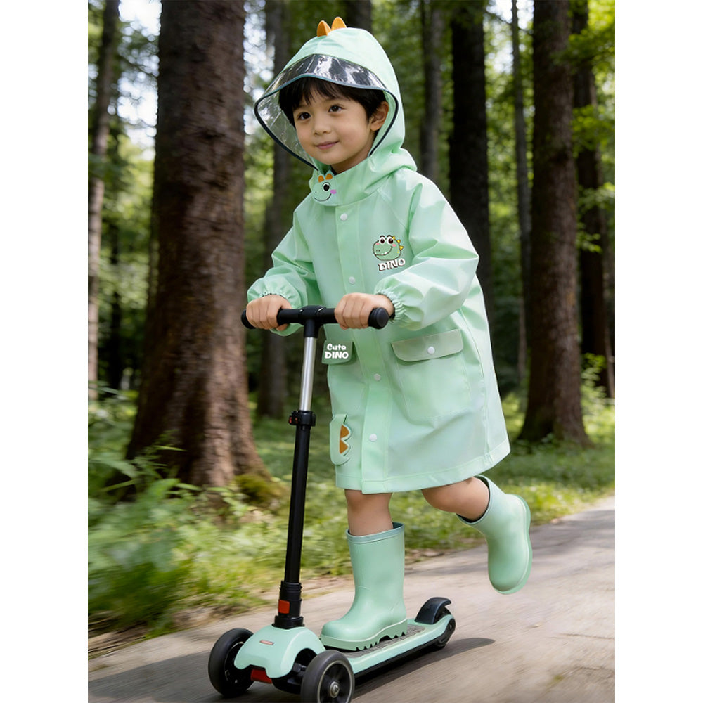 Child in a green raincoat and boots riding a scooter in a forest.