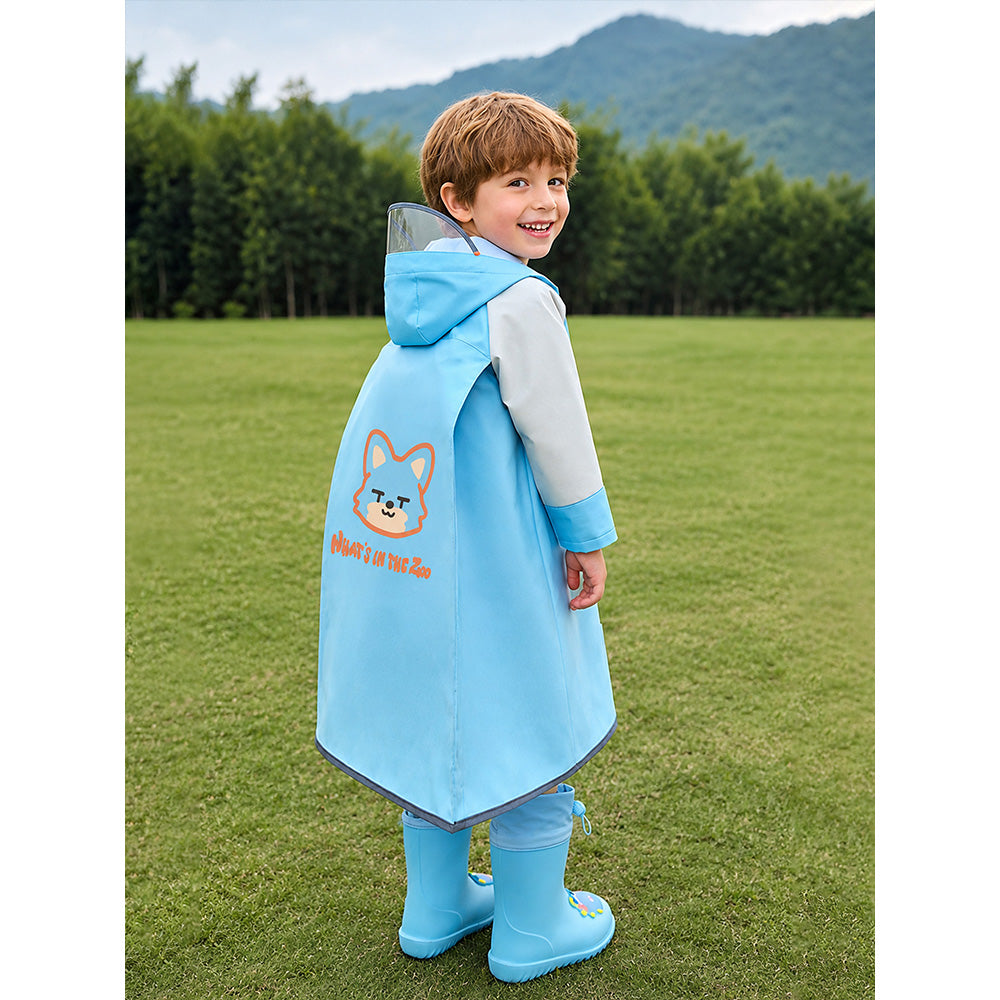 Child wearing a blue raincoat with a hood and cartoon character on a grassy field with trees and mountains in the background.