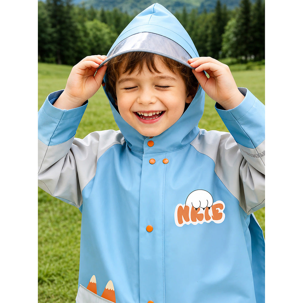 Child wearing a blue raincoat with a hood, standing outdoors with greenery in the background