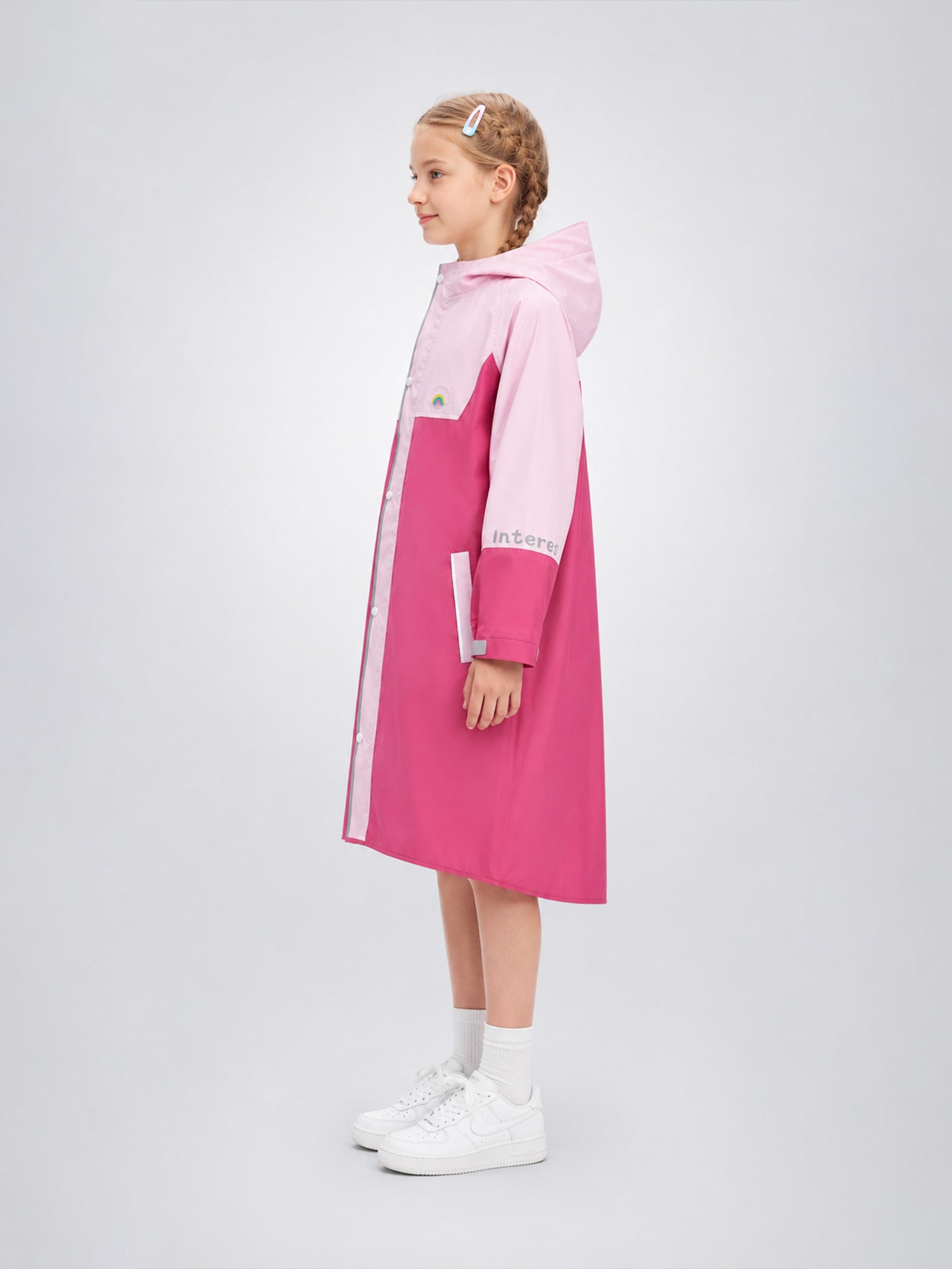 Young girl wearing a pink and white raincoat on a light gray background