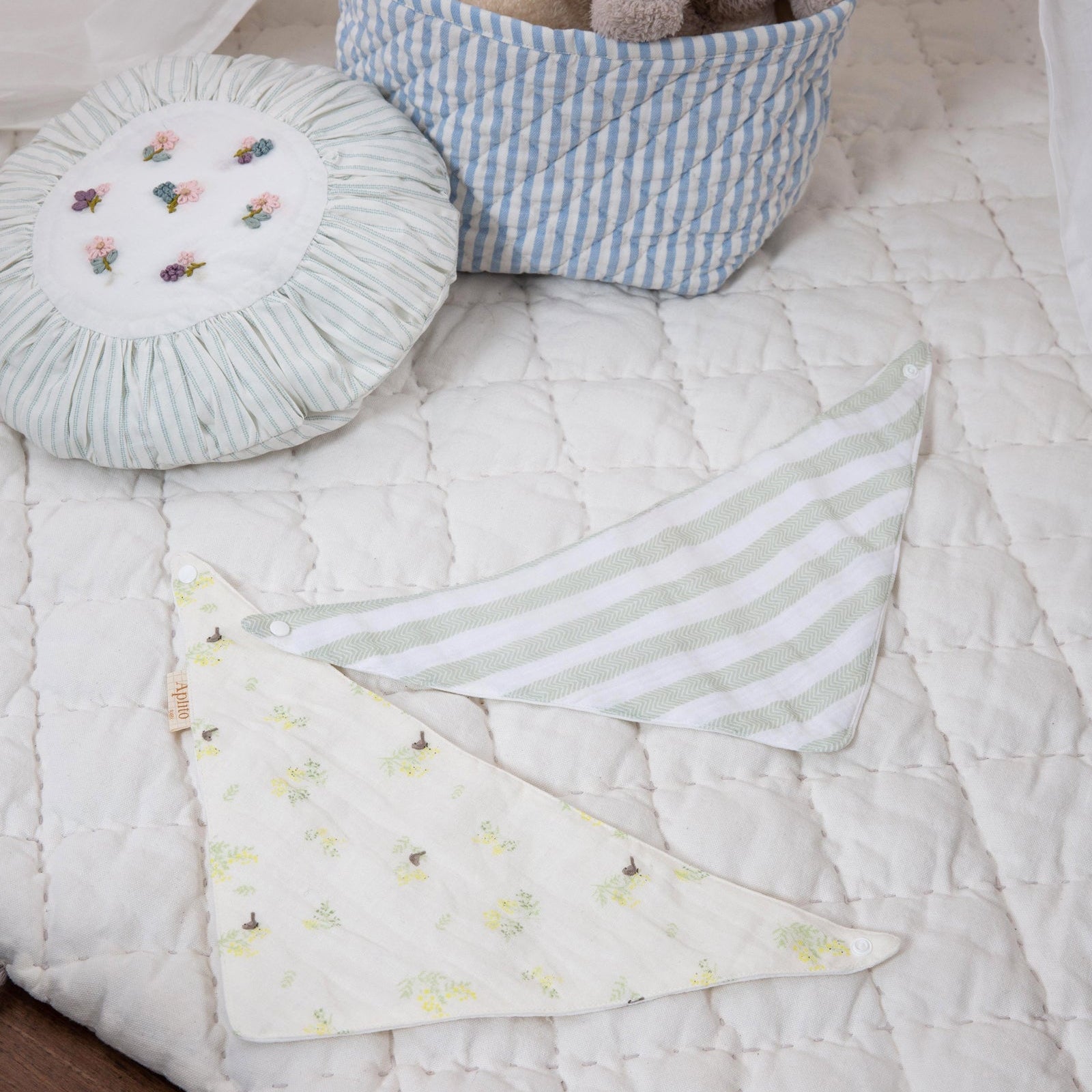 Baby blanket with tassels on a crib, surrounded by toys and a basket.