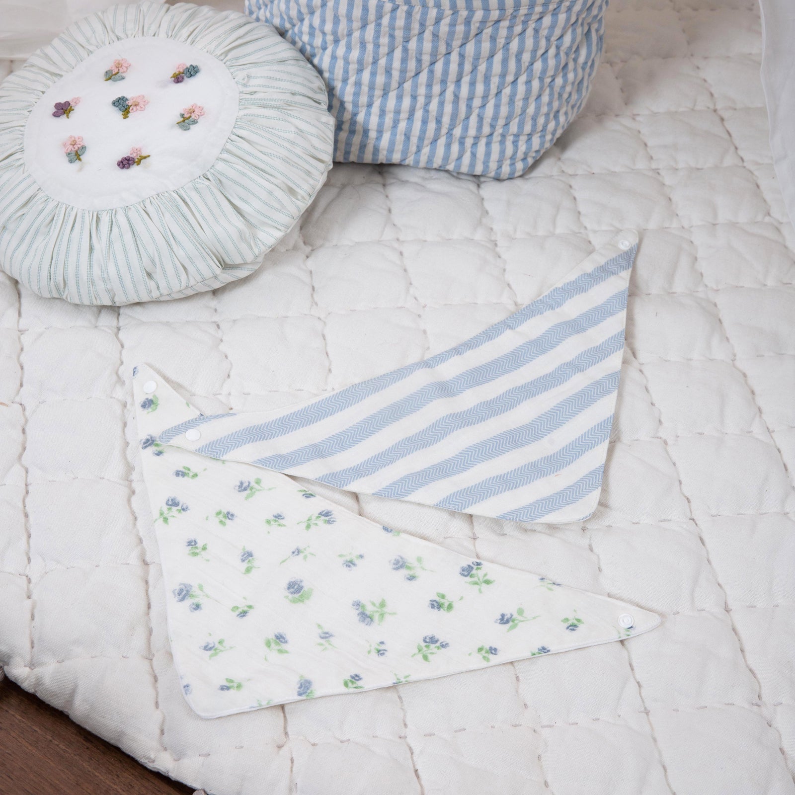Baby blanket with tassels, basket with toys, and round pillow on a crib