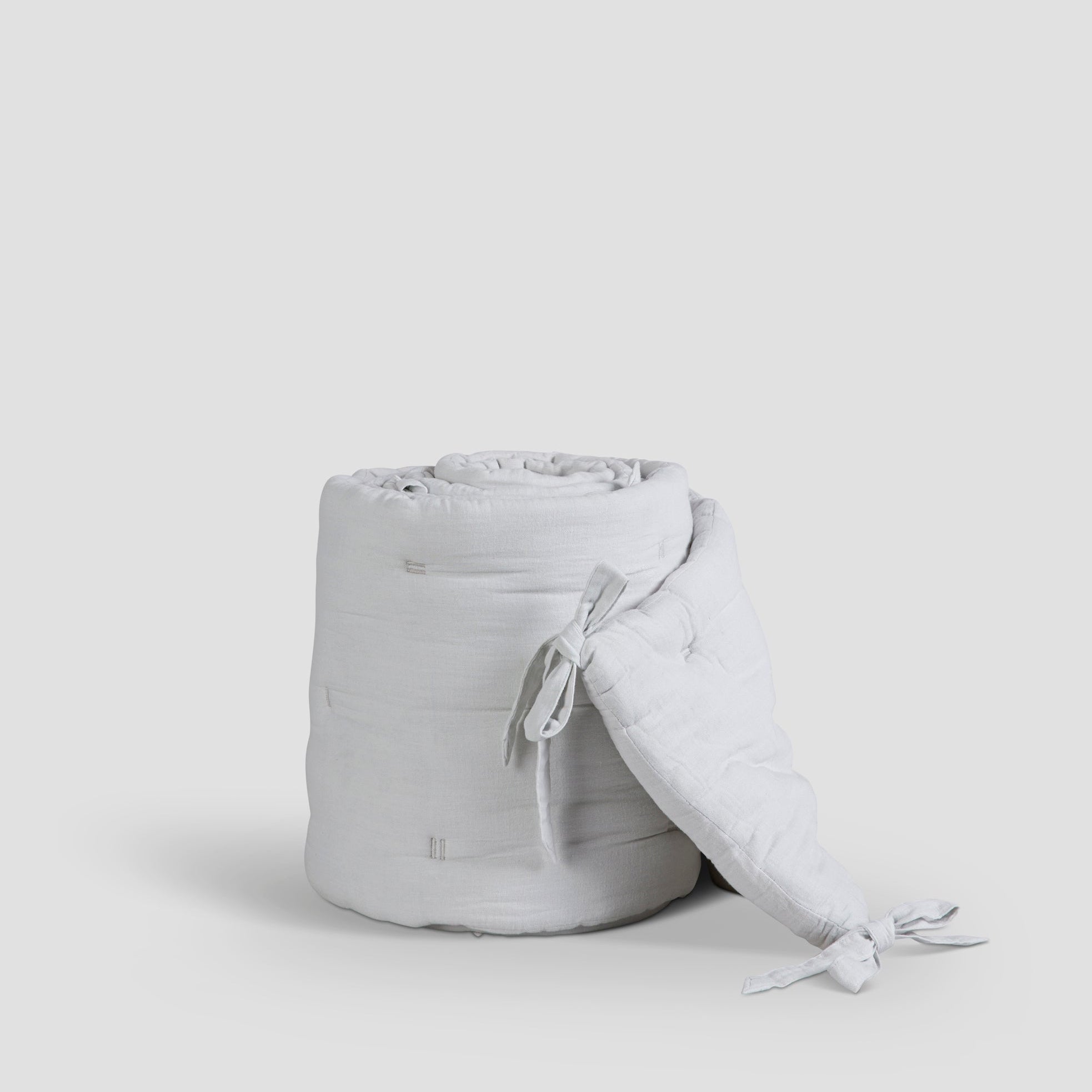 Light gray quilted bag with a matching pillow on a white background
