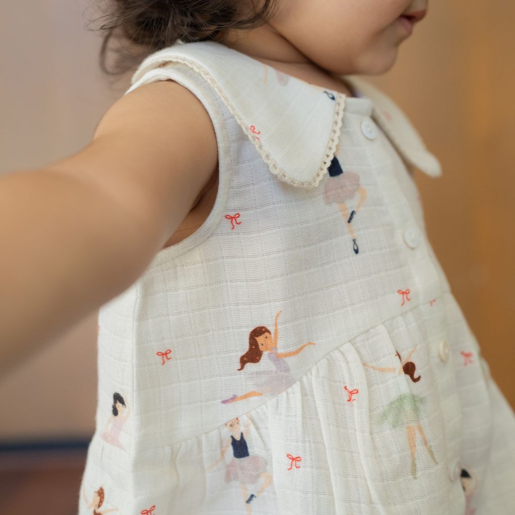 Child wearing a white dress with ballerina prints