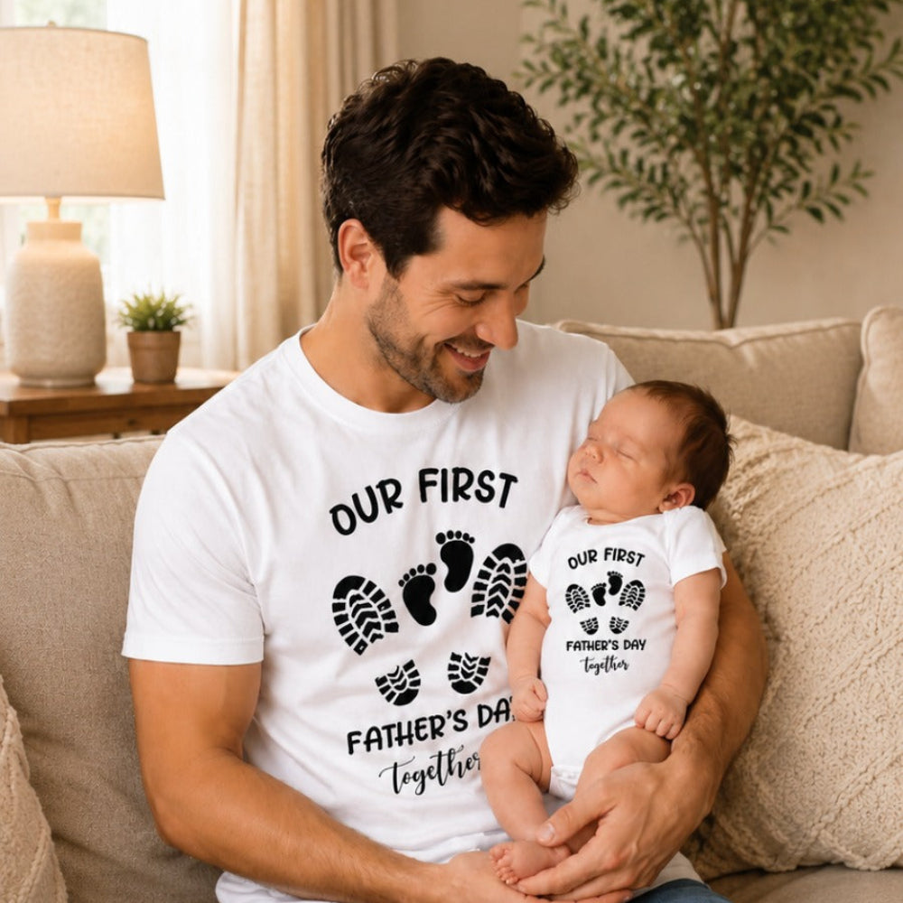 Man holding a baby wearing matching Father's Day t-shirts in a living room.