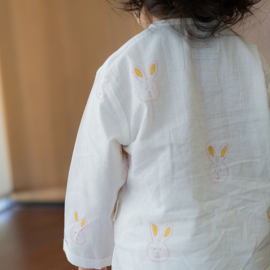 Child wearing a white outfit with bunny designs in a home setting