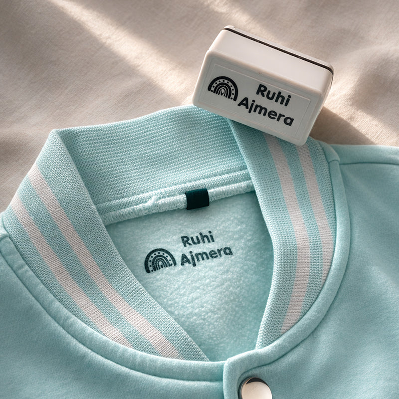 Personalised clothing name stamp used on a blue kids jacket with rainbow design
