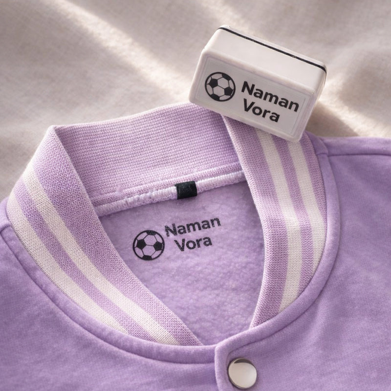 Clothing name stamp used on a purple kids jacket with ball design