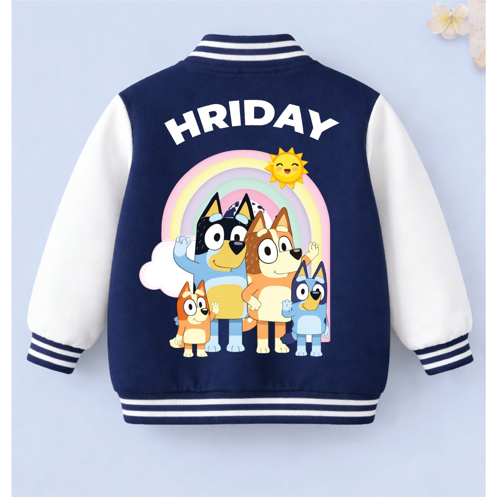 Personalised kids varsity jacket with cartoon character design and the name “HRIDAY” on a light blue background.