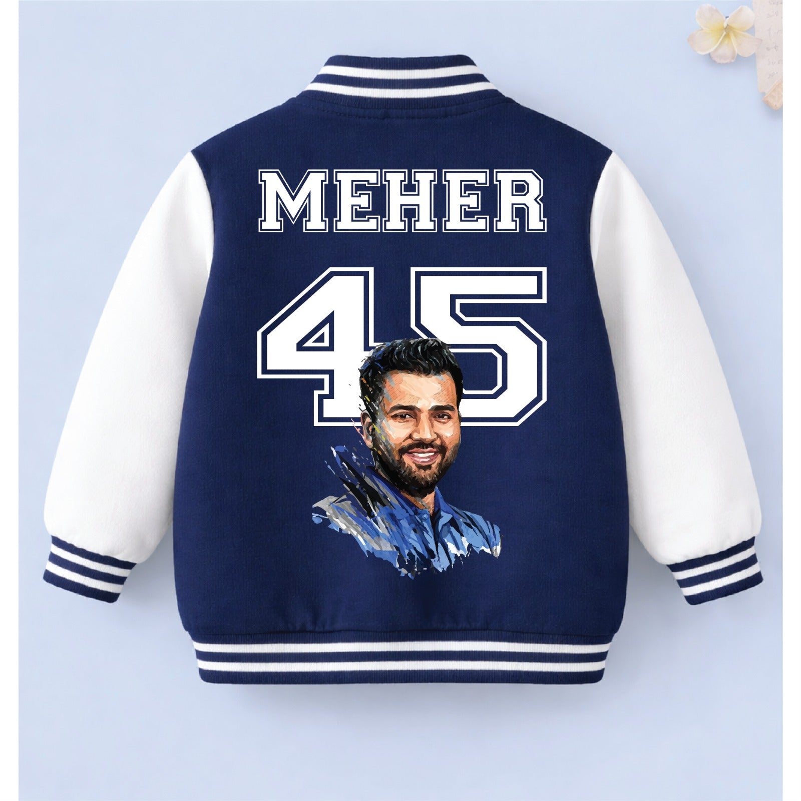 Navy blue personalised cricket varsity jacket with “MEHER 45” printed on the back against a light blue background.