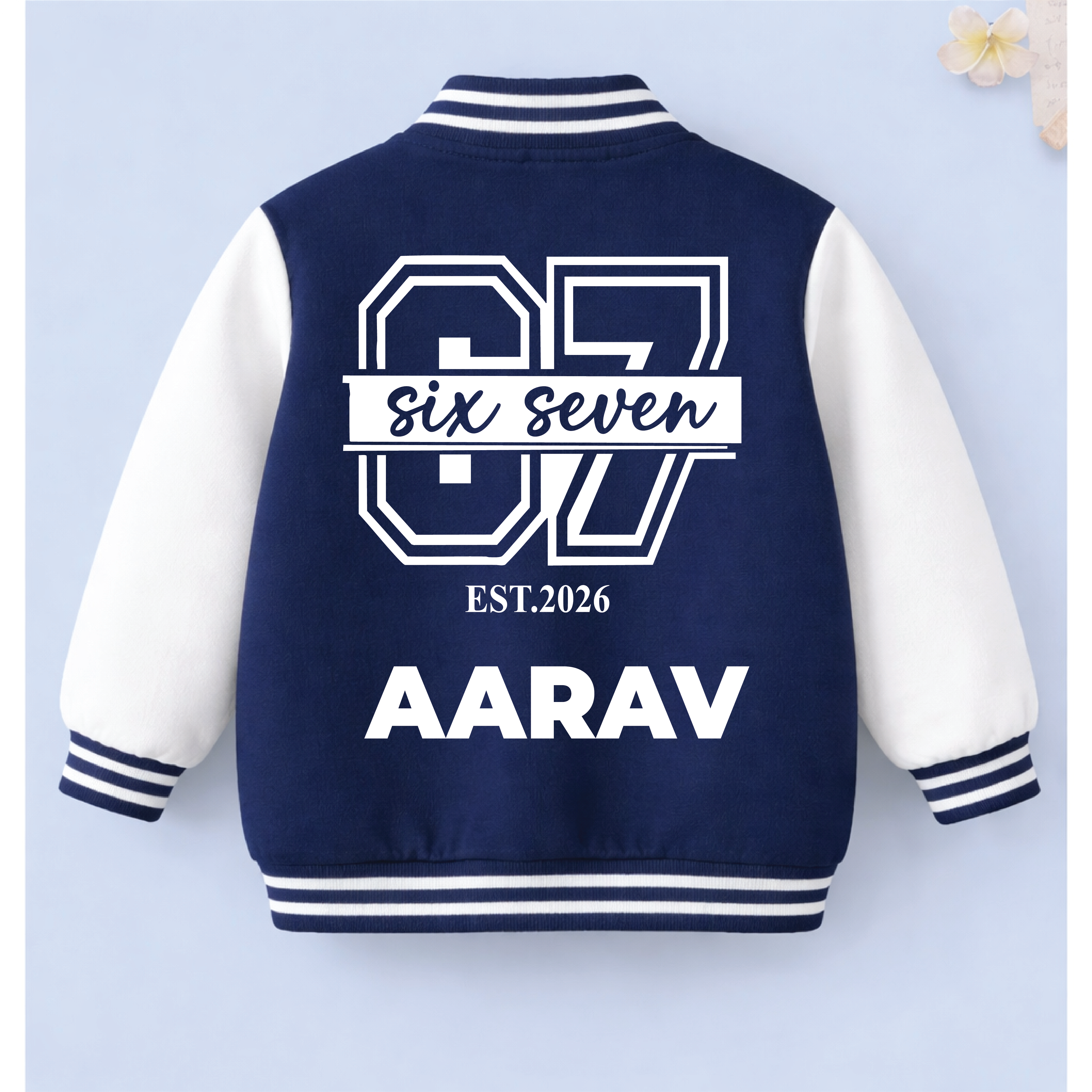 Navy and white personalised kids varsity jacket with custom name text on a light blue background.