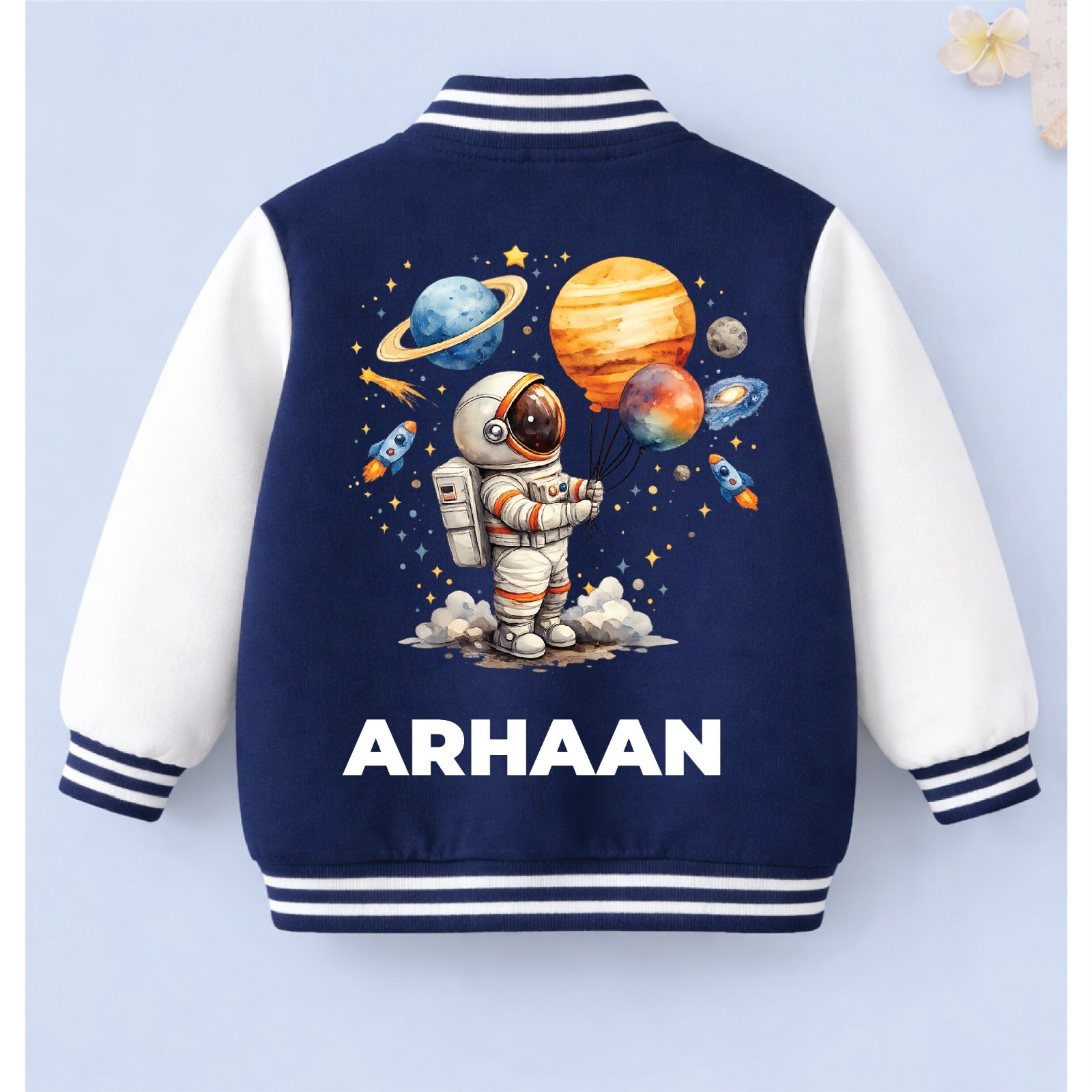 Personalised kids varsity jacket with space-themed design and the name “ARHAAN” on a light blue background.